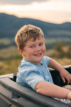 Little boy sitting in back of off-road buggy on farm