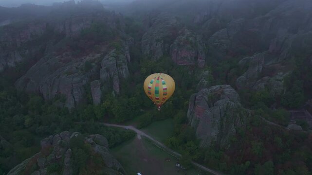 Belogradchik, Bulgaria - 01 December 2024: Aerial view of a hot air balloon over majestic rock formations and a tranquil valley, Belogradchik, Bulgaria.