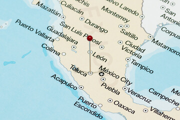 Macro photo of a red pin needle into Toluca city of Mexico political map 