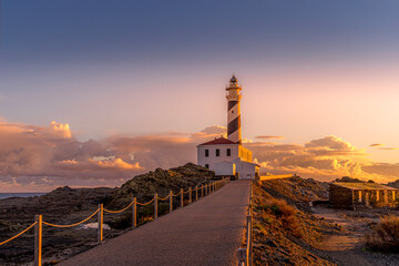 Morning light at the Favaritx Lighthouse, perched on a rugged coastline near Mahon, Menorca, in the...