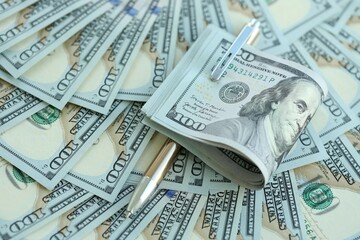 Golden pen clipping big amount of hundred dollar bills US banknotes