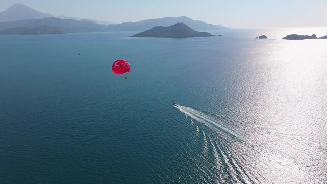 Aerial view of parasailing over the calm Mediterranean Sea with a scenic island and a boat, Fethiye, Turkey.