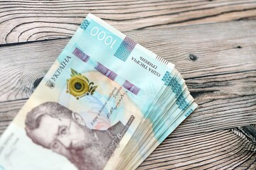 Big amount of ukrainian new one hundred hryvnia money bills with modern design on wooden background. Financial concept, business