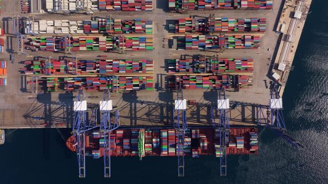 Aerial view of a busy container port with stacked shipping containers and cranes by the water, Perama, Greece.