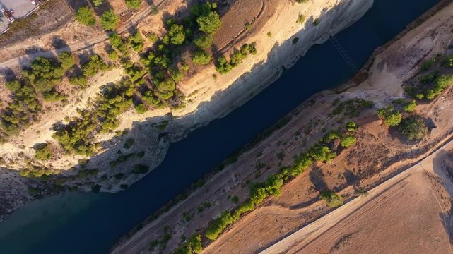 Aerial view of the beautiful Corinth Canal surrounded by lush green trees and tranquil water, Corinth, Greece.