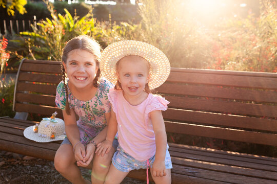 Two girls with easter hats together on park bench seat