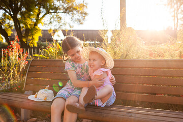Two happy girls with easter hats together on park bench seat