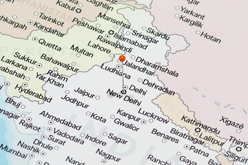 Macro photo of an Orange pin needle into New Delhi city of India political map 