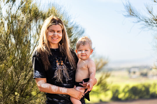 Portrait of first nations Australian mother with baby son by casuarina tree on cliff in country