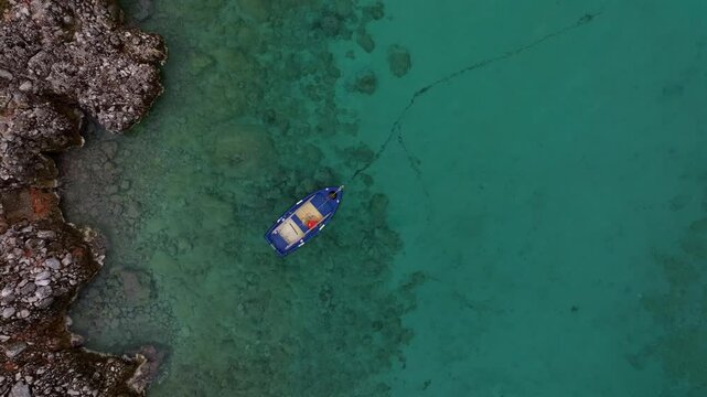 Aerial view of tranquil turquoise waters and rocky shore with a boat, Limeni, Greece.
