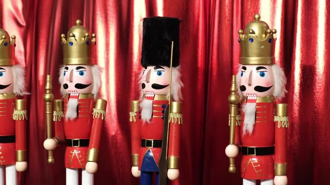 Wooden Nutcracker figures against a backdrop of scarlet fluttering fabric. Traditional style of Christmas decorations.