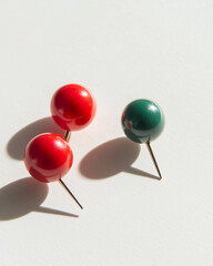 Three colorful push pins casting shadows on a white surface