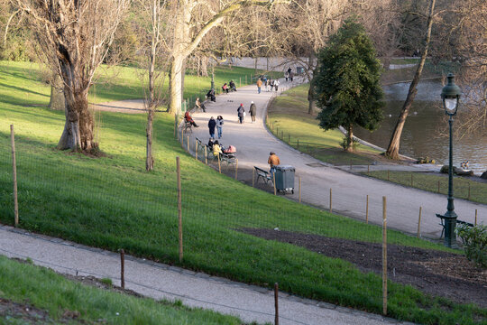 Visitors stroll along the pathways of Parc des Buttes-Chaumont in Paris enjoying a peaceful day in nature