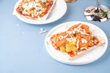 Matzah Pizza on light blue background with ingredients, cheese, tomato sauce. Food ideas and recipe for Jewish Pesach and Passover holidays