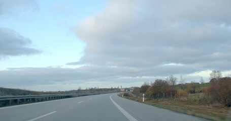 A beautiful highway scene unfolds with a cloudy sky hanging above and a picturesque countryside background