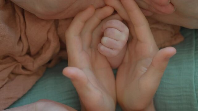 A touching family moment where father, mother, and elder son open their arms to form a flower-like pose, revealing the tiny hand of their newborn baby in the center. A symbolic gesture of love, unity