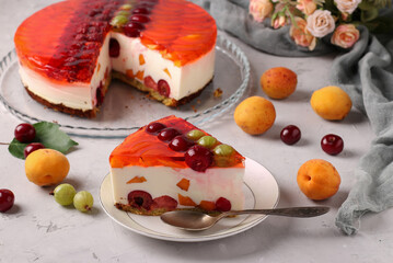 Festive jelly cake with berries on gray background with piece of cake on plate on a foreground