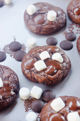 Homemade chocolate brownie cookies decorating with marshmallow on top on baking tray.