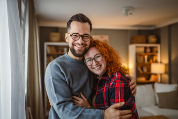 Portrait of beautiful happy couple stand, smile and hug at home