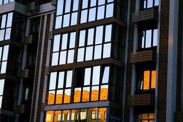 Modern buildings, walls and windows, reflections and sun rays. City view on a sunny day.