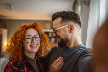 Self portrait of beautiful happy couple stand, smile and hug at home