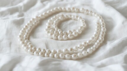 Obraz premium A delicate spiral of irregularly shaped white beads laid on a crisp, white linen tablecloth. The beads' natural imperfections add character.