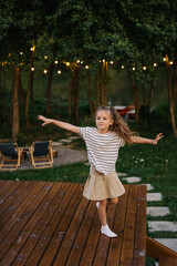.portrait of a happy 5-6 year old girl posing for a photo in the backyard of a country house