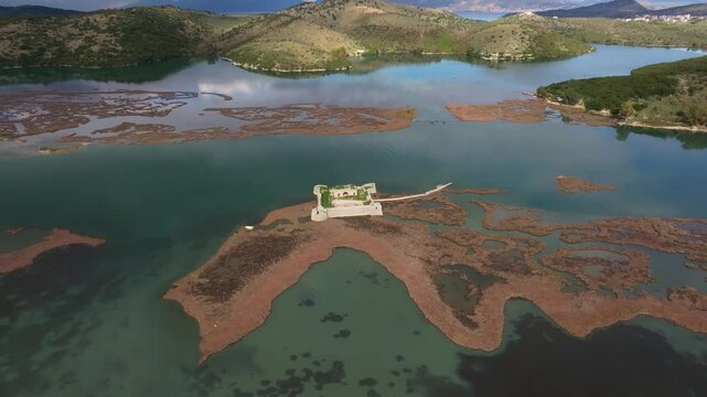 Aerial view of Ali Pasha's Castle and the serene Lake Butrint surrounded by beautiful mountains, Ksamil, Albania.