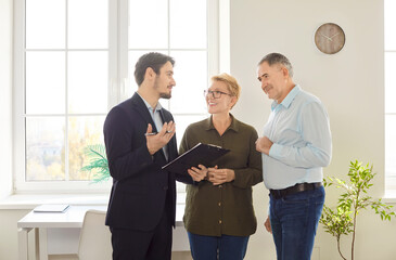 Elderly couple explores a property or apartment with a real estate agent or realtor, considering...