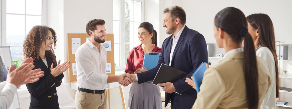 Happy proud male boss handshakes encouraging and thanking office employee for good job, shaking hand, getting promotion, recognition, respect and applause of colleagues introducing new team member
