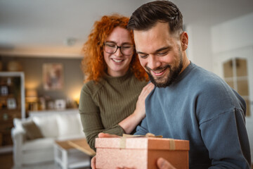young adult girlfriend surprise his boyfriend with gift box at home