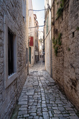 Obraz premium Morning walk along a romantic narrow street in the old town of Trogir on the Adriatic coast, Dalmatia, Croatia