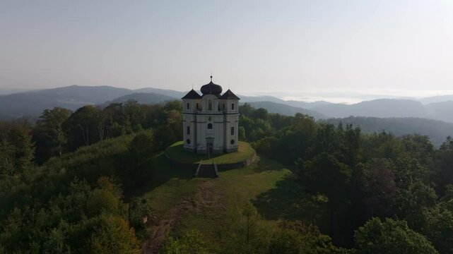 Aerial view of the historic Kostel sv. Jana Krtitele a Panny Marie Karmelske church surrounded by tranquil forests and hills, Smolotely, Czech Republic.