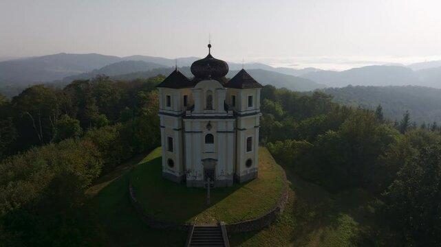 Aerial view of the historic Kostel sv. Jana Krtitele a Panny Marie Karmelske church surrounded by tranquil forest and picturesque landscape, Smolotely, Czech Republic.