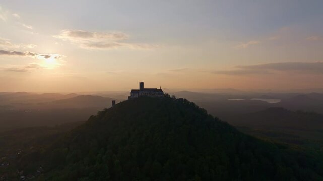 Aerial view of Bezdez Castle at sunset surrounded by lush hills and a serene sky, Bezdez, Czech Republic.