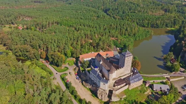 Aerial view of kost castle surrounded by lush forest and a serene river, Dobsin, Czech Republic.
