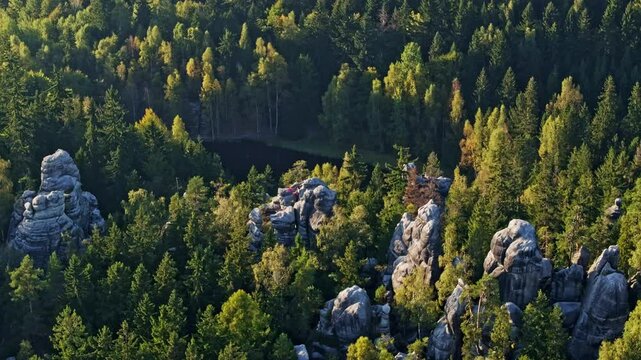Aerial view of cerne jezirko surrounded by lush forest and rocky formations, Teplice nad Metuji, Czech Republic.