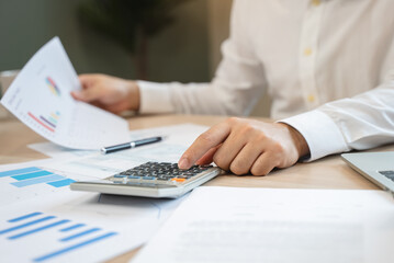 Close up hand of professional accountant review tax paperwork and signing signature on the table in workplace