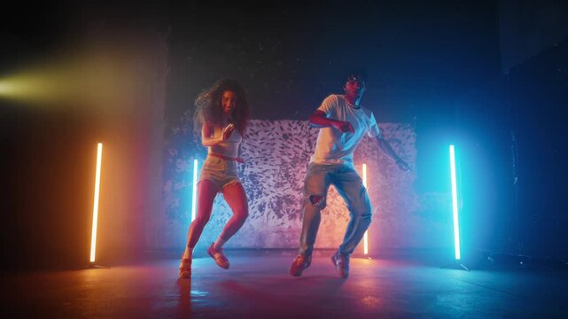 People dancing reggaeton and dancehall in dance studio, black man and woman. Active dance performance, African American dancers performing modern choreography, street style dance, slow motion shot
