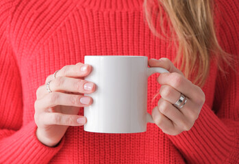 woman hands with rings holding white mug mockup, red sweater background