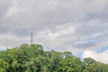 Obraz premium Cloudy Day Over Lush Green Hilltop with Transmission Tower
