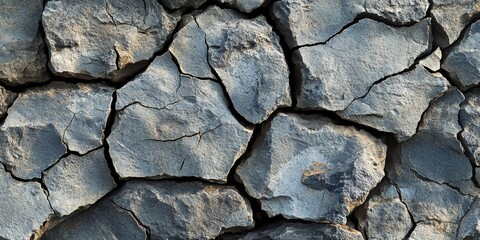 Fototapeta premium Cracked stone rock texture serves as an intriguing background, highlighting the rugged beauty of cracked stone rock and its unique patterns that enhance the visual appeal of any composition.