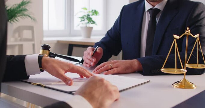 Close up shot of a lawyer or attorney working with a client during a meeting in an office, discussing legal documents, contract negotiations, and providing law services during conversation.