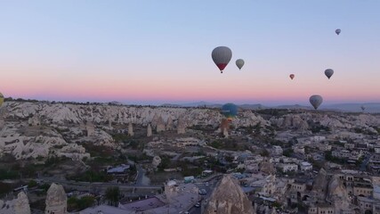 Goreme, Turkey - 01 December 2024: Aerial view of colorful hot air balloons at sunrise over the picturesque Cappadocia valley with majestic rock formations, Goreme, Turkey.