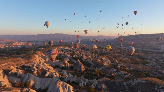 Goreme, Turkey - 01 December 2024: Aerial view of hot air balloons over rock formations at sunrise, Goreme, Turkey.