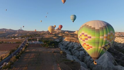 Goreme, Turkey - 01 December 2024: Aerial view of hot air balloons over a beautiful valley at sunrise with stunning geological formations, Goreme, Turkey.
