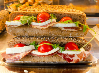 Gourmet Sandwich with Fresh Tomatoes, Cheese, and Greens,Savor a delicious sandwich made with fresh ingredients: ripe cherry tomatoes, creamy cheese, and greens on hearty seeded bread.