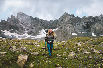 Woman climbing mountains with trekking poles and backpack gear travel adventure lifestyle hiking solo female traveler exploring wild nature trails, active vacations outdoor extreme tour
