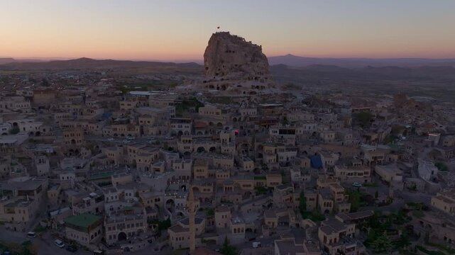 Aerial view of Uchisar Castle at sunset with ancient stone buildings in Cappadocia, Uchisar, Turkey.