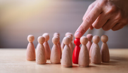 Naklejka premium Hand pointing at red wooden figure among others. Uniqueness, leadership or selection concept.